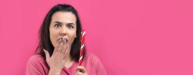 Güzel, güzel, neşeli, düz kahverengi saçlı bir kadının portresi. Kırmızı şeker kamışı Noel 'ini ısırmaya çalışıyor..