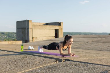 Spor giyimli, yılan derisi baskılı genç ve zayıf bir atletik kız bir takım egzersizler yapıyor. Fitness ve sağlıklı yaşam tarzı.