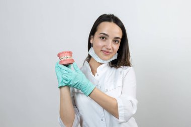 Beyaz önlüklü dişçi kız bir alay diş tutuyor..