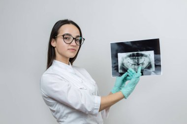 Beyaz önlüklü kız dişçi hastanın dişlerinin fotoğrafını tutuyor..