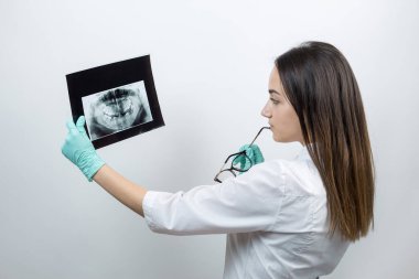 Beyaz önlüklü kız dişçi hastanın dişlerinin fotoğrafını tutuyor..