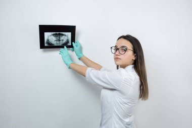 Beyaz önlüklü kız dişçi hastanın dişlerinin fotoğrafını tutuyor..