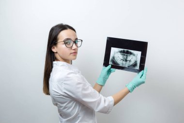 Beyaz önlüklü kız dişçi hastanın dişlerinin fotoğrafını tutuyor..