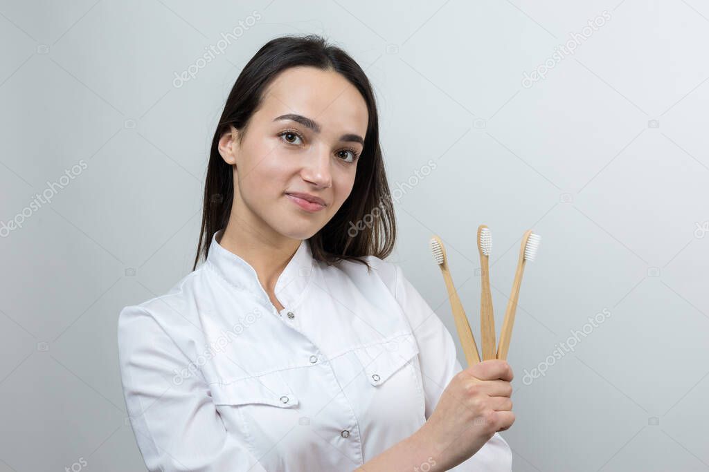 A young brunette girl holds an ecological toothbrush in her hands. A girl in a white coat promotes zero waste.