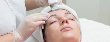 Yüz bakımı. Güzellik uzmanı güzellik salonunda fırça kullanarak yüzüne güzellik maskesi takıyor.