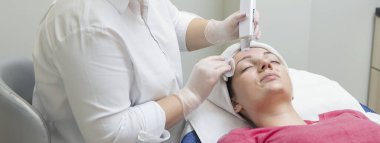 Yüz bakımı. Güzellik uzmanı güzellik salonunda fırça kullanarak yüzüne güzellik maskesi takıyor.