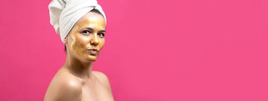 Yüzünde altın besleyici maske olan beyaz havluyla kadın portresi. Cilt temizleme eko organik kozmetik rahatlama konsepti.