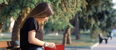 Genç bir kız parkta bir bankta oturur ve notlar alır. Serbest stil giyinmiş. İş kadını müşterilerle telefonda konuşuyor. Dinlenme ve kahve içme zamanı.