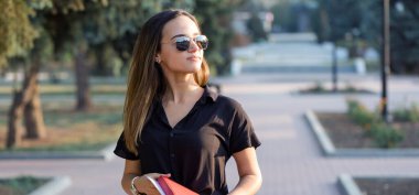 Genç bir kız parkta bir bankta oturur ve notlar alır. Serbest stil giyinmiş. İş kadını müşterilerle telefonda konuşuyor. Dinlenme ve kahve içme zamanı.