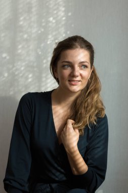 Arka planda, gölgeli gri bir duvarın üzerinde, penceresinden yansıyan doğal ışık olan güzel bir kızın portresi..