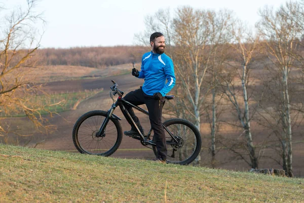 Cyclist in pants and fleece jacket on a modern carbon hardtail bike with an air suspension fork. The guy on the top of the hill rides a bike.