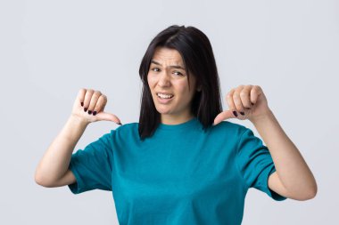 Mavi kolsuz tişörtlü genç bir esmer, olumsuz bir ifadeyle başparmak hareketi yapıyor.