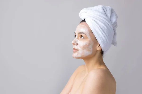 頭の上の白いタオルの女性の美しさの肖像画は顔にクリームを適用します スキンケアクレンジングエコ有機化粧品スパリラックスコンセプト — ストック写真