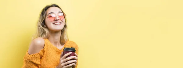 オレンジのセーターに身を包んだグラマーな女性 黄色の背景にコーヒーを飲みながら — ストック写真