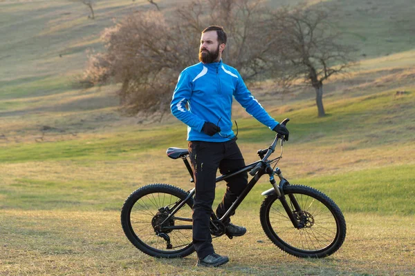 Cyclist in pants and fleece jacket on a modern carbon hardtail bike with an air suspension fork. The guy on the top of the hill rides a bike.