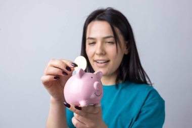 Kızın elinde pembe bir kumbara ve bozuk para var. Zenginlik ve birikim kavramı.