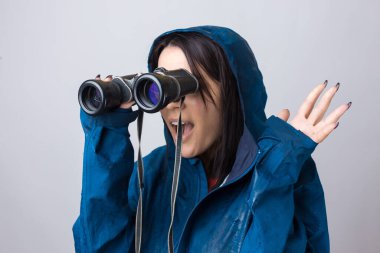 Mavi yağmurluklu bir turist kız elinde dürbünle uzaklığa bakıyor, casuslar..