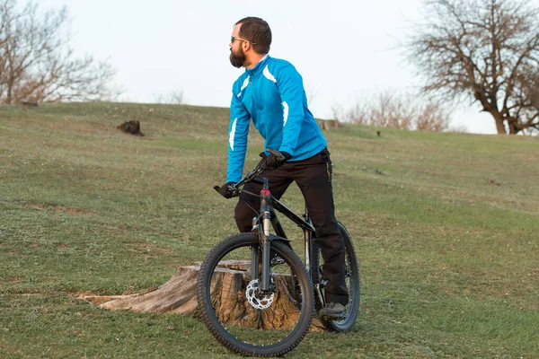 Cyclist in pants and fleece jacket on a modern carbon hardtail bike with an air suspension fork. The guy on the top of the hill rides a bike.