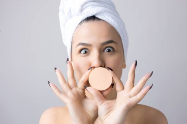 Kafasında beyaz havluyla güzel bir kadın portresi ve pembe bir kalbe bakan bir vücut için sünger. Cilt temizleme eko organik kozmetik rahatlama konsepti.