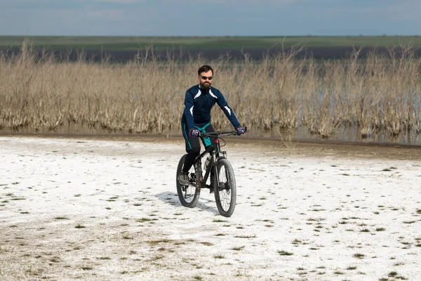 Cyclist in pants and fleece jacket on a modern carbon hardtail bike with an air suspension fork.