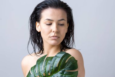 Doğal yeşil palmiye yaprağı portresi olan bir kadın. Moda, güzellik, makyaj, kozmetik.