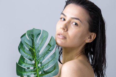 Doğal yeşil palmiye yaprağı portresi olan bir kadın. Moda, güzellik, makyaj, kozmetik.