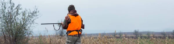 狩猎期 秋季开放 一个拿着猎枪的猎人穿着猎服在秋天的森林里寻找奖品 一个人拿着武器和猎狗站在那里追踪猎物 — 图库照片