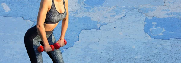 一个穿着腿和上衣的身材苗条的女运动员站在水泥墙边 脚垫上有训练用的垫子 在练习之间休息 — 图库照片