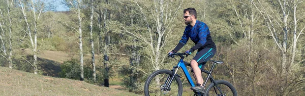 Cyclist in pants and fleece jacket on a modern carbon hardtail bike with an air suspension fork. The guy on the top of the hill rides a bike.