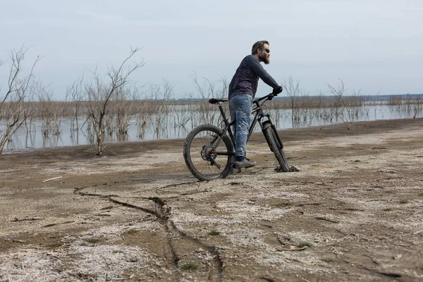 現代のマウンテンバイクで残酷な髭の男をスポーツ 湖に捨てられた塩の中のサイクリスト — ストック写真