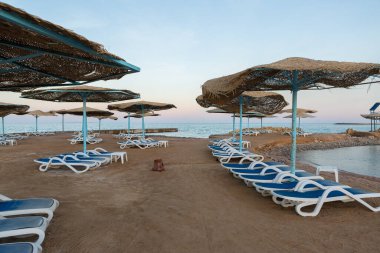 Güverte sandalyeleri ve şemsiyesiz sahil şeridi. Terk edilmiş tatil köyü.