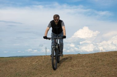 Modern dağ bisikletindeki vahşi sakallı adam. Gölün kenarındaki tuzlu bir yerde bir bisikletçi..
