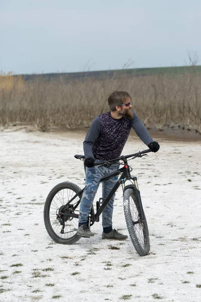 現代のマウンテンバイクで残酷な髭の男をスポーツ 湖に捨てられた塩の中のサイクリスト — ストック写真