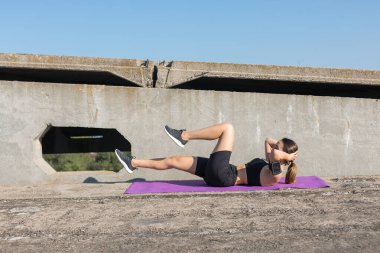 Spor giyimli, yılan derisi baskılı genç ve zayıf bir atletik kız bir takım egzersizler yapıyor. Fitness ve sağlıklı yaşam tarzı.