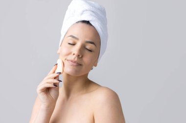 Kafasında beyaz havluyla güzel bir kadın portresi ve pembe bir kalbe bakan bir vücut için sünger. Cilt temizleme eko organik kozmetik rahatlama konsepti.