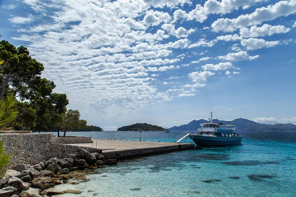 Deniz, dağlar ve güneşli gökyüzü güzel bulutlar ile arka plan üzerinde pier yakınındaki küçük bir tekne