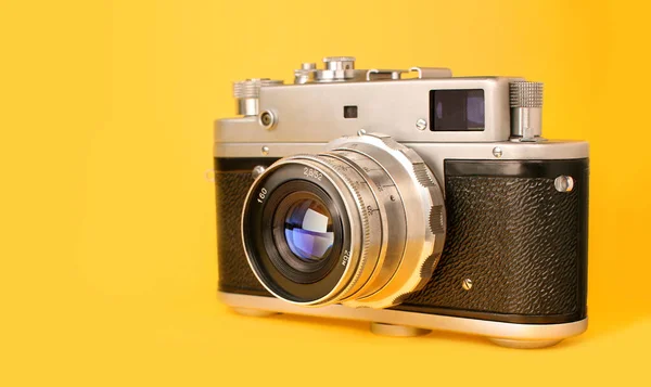 Retro, vintage film photo camera isolated on yellow colourful trendy modern fashion background. Camera lens with reflections. Film camera. Creative, minimalism