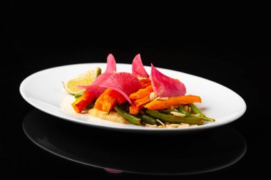 Siyah arka planda beyaz tabakta kuşkonmaz ve kereviz püresi ile fırında tatlı patates.