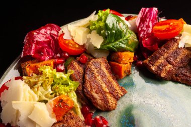 Kızarmış biftek ve yeşil tabakta Worcester soslu sıcak salata.