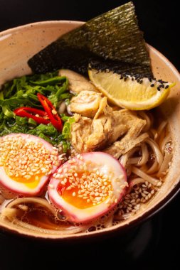 Erişteli makarna ve siyah arka planda bir tabakta tavuk.