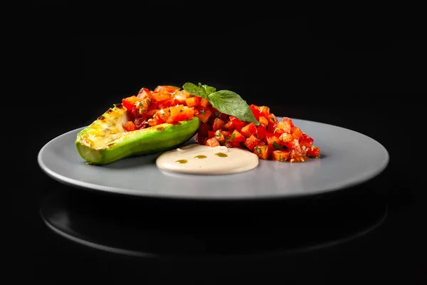 Siyah arka planda tahini soslu ızgara avokado salatası.