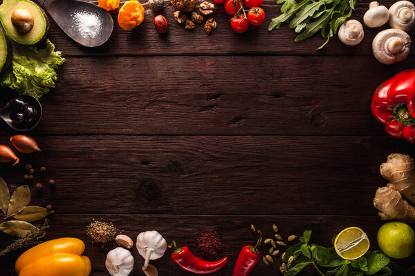 Перец, чеснок, имбирь, лавровый лист, специи, лайм, деревянная ложка с солью на темном деревянном фоне. Компоновка фона со свободным текстовым пространством. Принято. Вид сверху. Плоская еда
