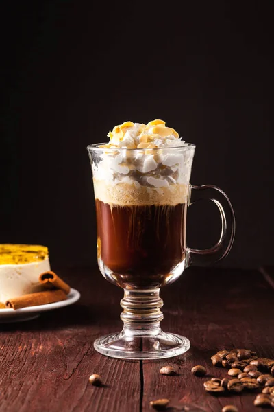 Kahverengi ahşap bir masada şeffaf bir bardakta espresso, İrlanda viskisi ve krema üzerine kurulu kahve kokteyli. Alkolik kahve kokteyli. Alkol iç.