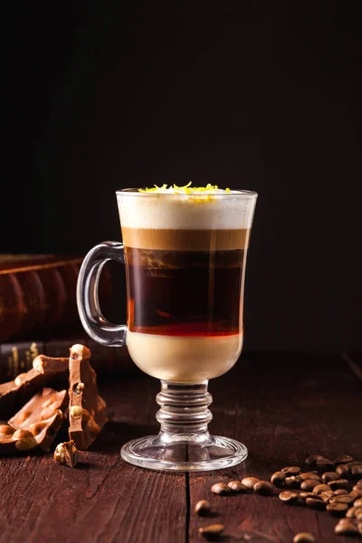 Coffee cocktail based on espresso, Irish whiskey, rum and whipped cream in a transparent glass on a brown wooden table. Alcoholic coffee cocktail. Alcohol drink