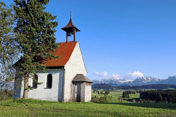 Una pequeña capilla blanca frente a los Alpes Allgu — Foto de Stock