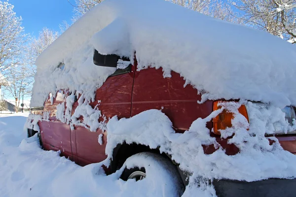 Μια χιονισμένη κόκκινο αυτοκίνητο χειμώνα στο δρόμο — Φωτογραφία Αρχείου