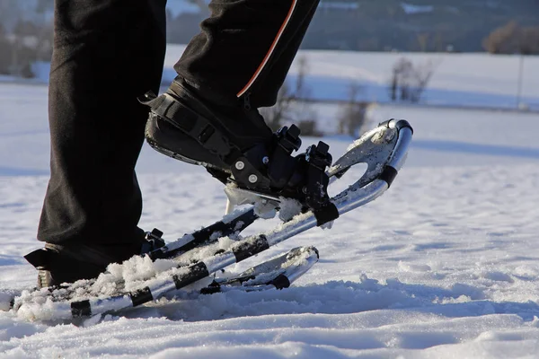 A woman runs with snow shoes through the snow — Stock Photo, Image