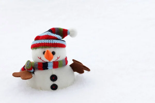 Un muñeco de nieve con gorra y bufanda en la nieve fría — Foto de Stock