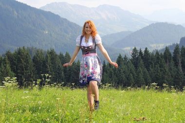 Dirndl dağlarda genç bir kızıl saçlı kadın