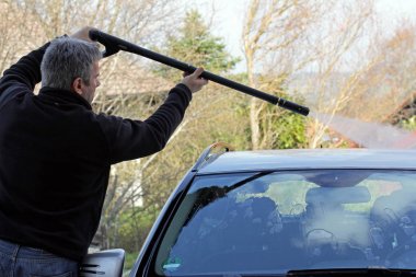 Bir adam çatı arabasını yıkar.